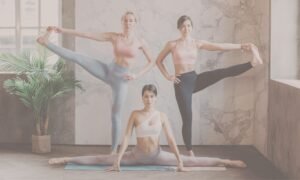 Three women demonstrating advanced yoga poses including splits and standing leg extensions in marble studio with natural light